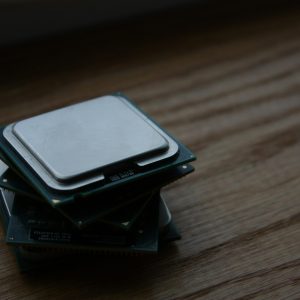 Close-up of multiple computer CPUs stacked on a wooden surface, showcasing technology components.