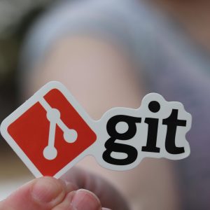 Close-up of a person holding a Git sticker, emphasizing software development.